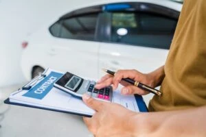 Man fills out car insurance claim form. Learn what the minimum auto insurance coverage is in New York