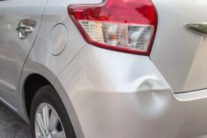 A silver car has a small dent after a minor car accident