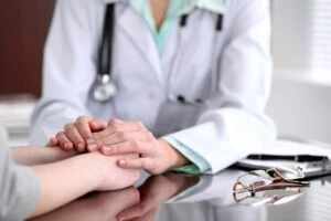 Female doctor holding hands of patient illustrating the concept of Bad Faith Insurance