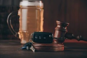 Glass of beer car keys and judge gavel on a table representing the concept of DUI Accident