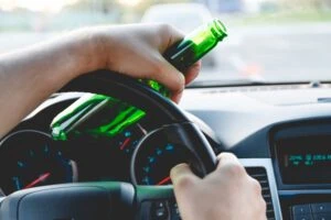 Drunk man driving a car with a bottle in representing the concept of a DUI Accident