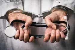 A doctor with his hands in handcuffs. Contact an Oakland medical malpractice lawyer.