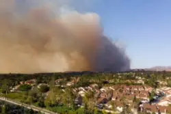 Smoke rises with a wildfire near a neighborhood. What types of wildfire damages can you recover compensation for?
