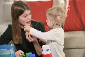 A little boy with cochlear implants playing with his mother