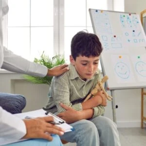 A sad-looking boy experiencing school abuse in Las Vegas is comforted by a counselor.