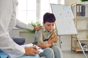 A sad-looking boy experiencing school abuse in Las Vegas is comforted by a counselor.