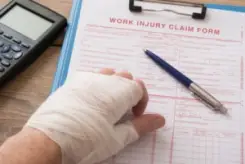 bandaged hand with a workers’ comp form
