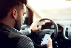 man checking his phone behind the wheel