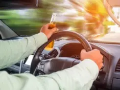 man driving with a beer bottle in hand