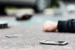 person lying on the street next to their broken phone