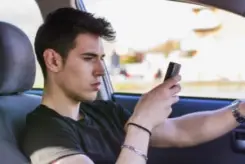 young guy texting behind the wheel