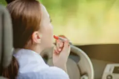 woman applying her makeup while driving