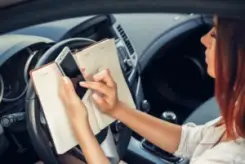 woman checking her phone behind the wheel