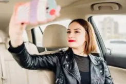 young girl taking a selfie behind the wheel