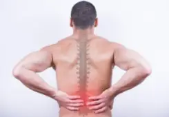 rear view of man holding back from pain in spine