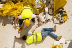 trabajador de construcción revisa a colega lesionado en sitio de trabajo