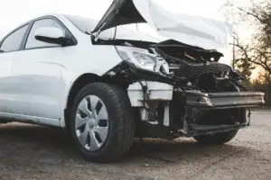 front of a broken white car after crash
