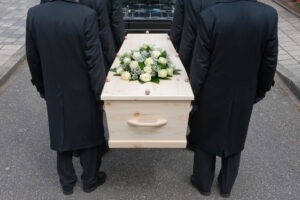 pall bearers carrying a coffin into a car