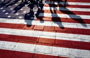 Sombras de personas caminando por calles con la bandera pintada de los Estados Unidos. ¿Qué es el asilo?