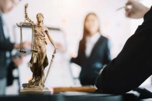 statue of justice with scales and auction hammer, the team meeting at the law firm behind the concept of in office law.