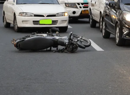 Motorcycle lying in the middle of a road in front of traffic after an accident.
