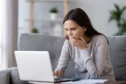 Shocked stressed young woman reading bad online news looking at broken laptop screen