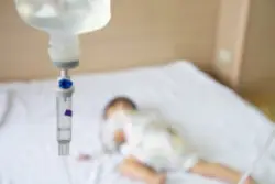 A baby suffering from infant meningitis on an IV in a hospital bed