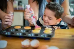 A child with intellectual disabilities making cupcakes with an adult