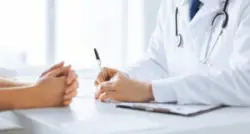 A doctor and a patient discussing things with their hands on a table