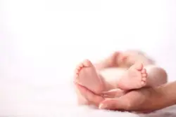A newborns feet being held by someone's hands