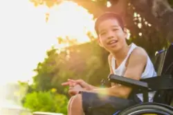 A child with cerebral palsy smiling in their wheelchair