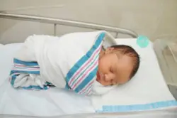 A newborn baby in a hospital crib