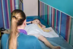 A child with erbs palsy laying on a table with medical staff watching