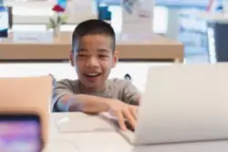 A child with Cerebral palsy at a table looking at a computer