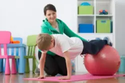 A child with cerebral palsy balancing his legs on a ball