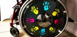 A wheel chair with handprints in paint on the wheel
