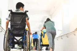 A person in a wheelchair going down a hospital hallway