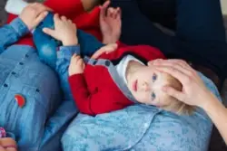A child with cerebral palsy laying in their parent's laps