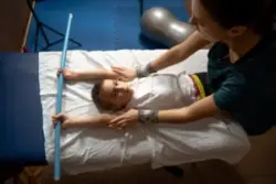A child with cerebral palsy doing stretch therapy on a table