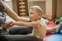 A child with cerebral palsy doing stretches with an adult