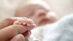 baby holding moms hand while sleeping