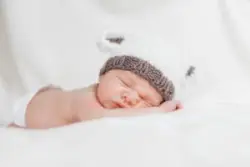 baby sleeping on belly in white hat