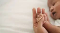 sleeping baby holding parent’s thumb