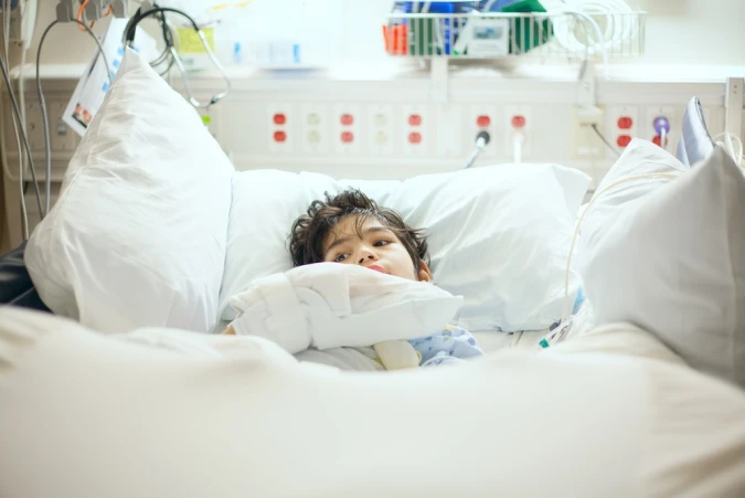 A child with cerebral palsy lies in a hospital bed.