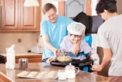 A father bakes cookies with his teen son and younger son in wheelchair