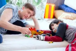 father playing with disabled son on floor