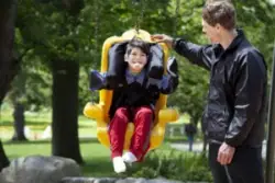 father pushes his son on a handicap-accessible swing at park