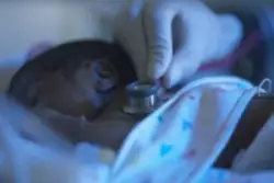 Medical staff member examines a newborn
