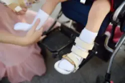 A mother puts leg braces on a child with cerebral palsy