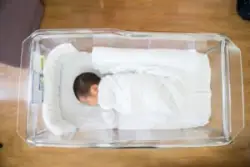 newborn baby lies in a hospital bed